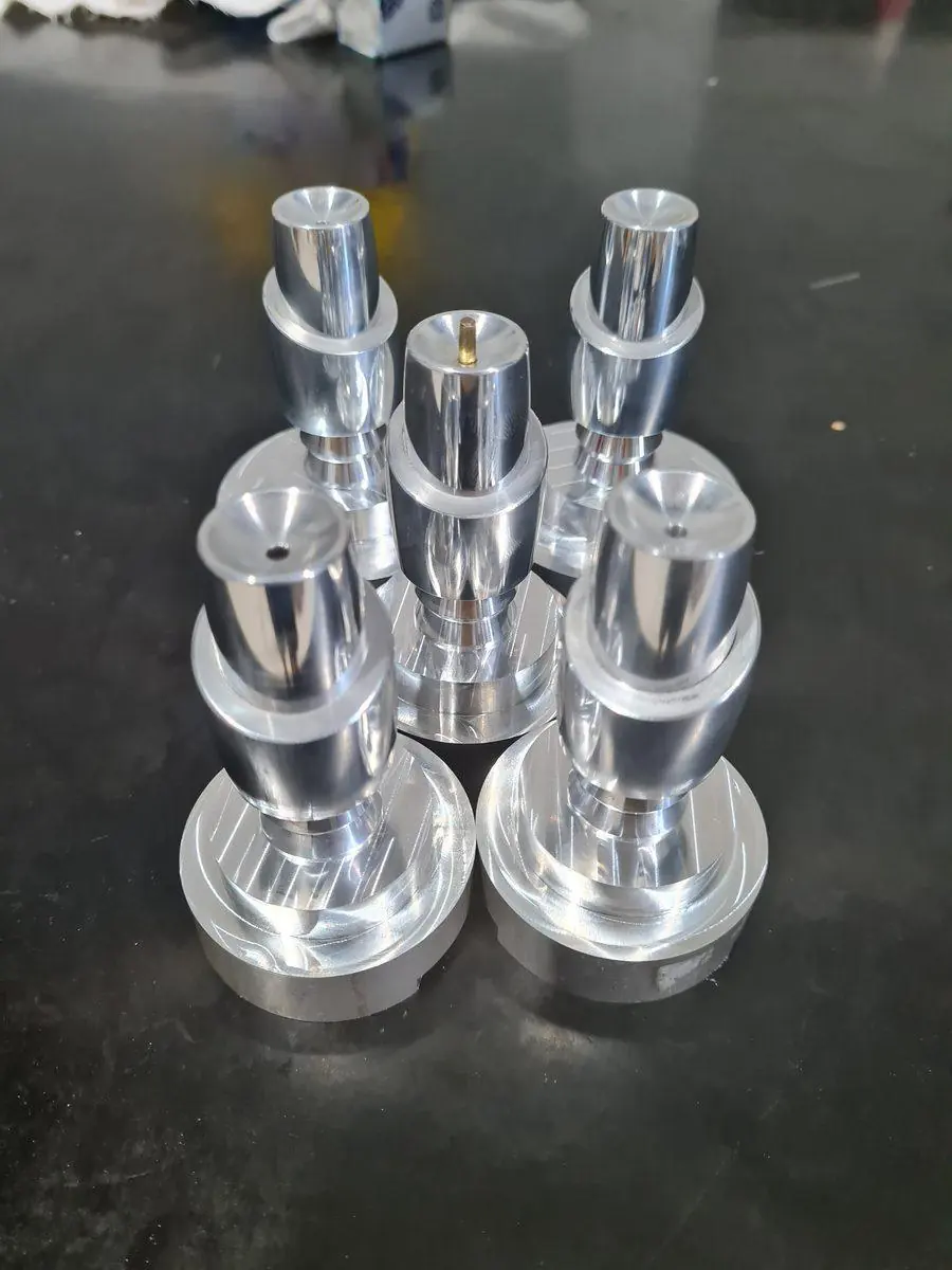 A run of identical turned aluminium components stood on the bench