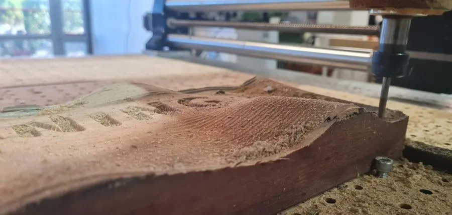 A hardwood slab clamped on the router bed part-way through machining