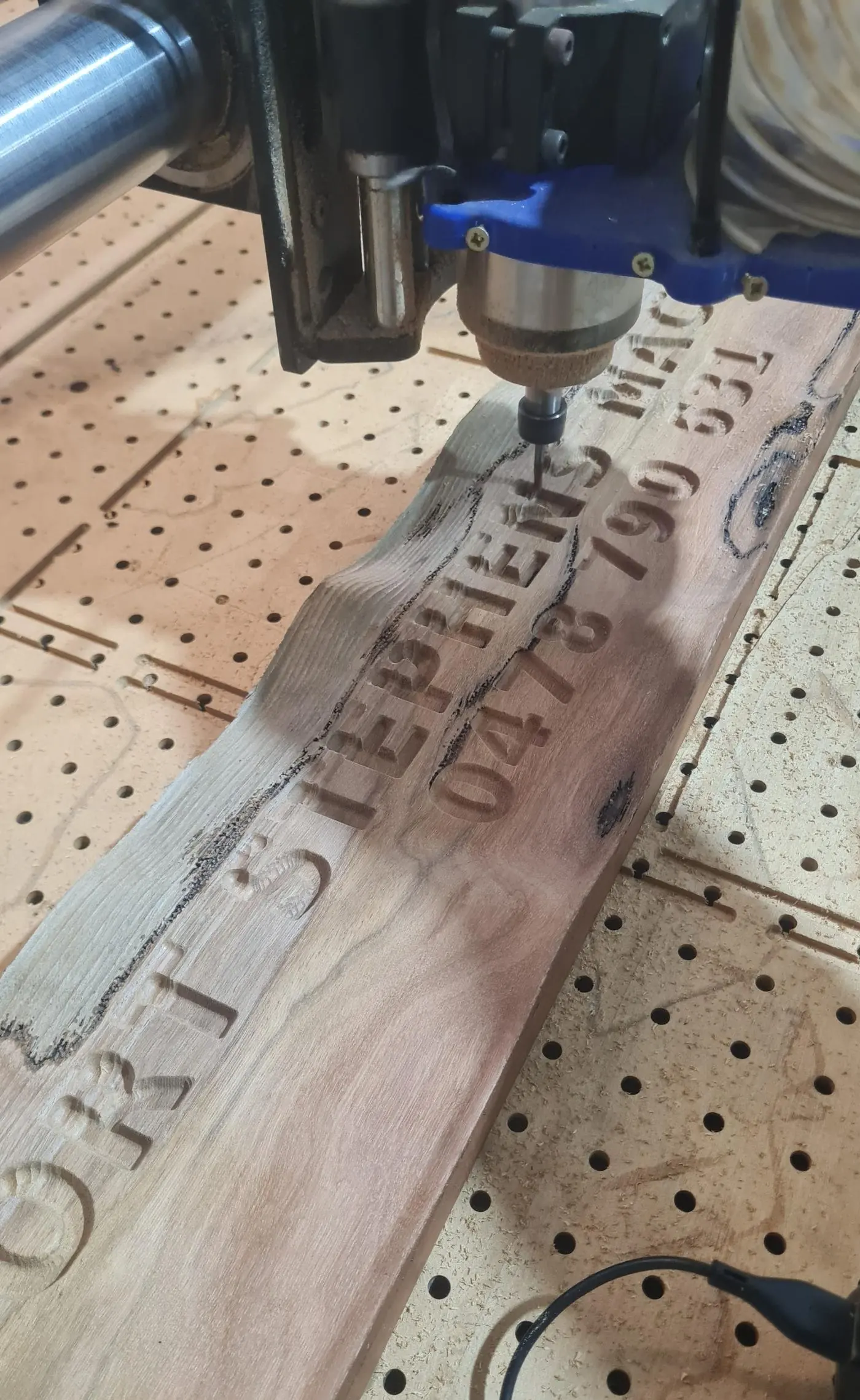 A carved timber sign with lettering, on the router bed