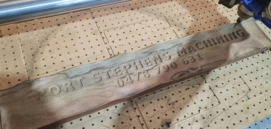 A finished carved hardwood sign on the router bed